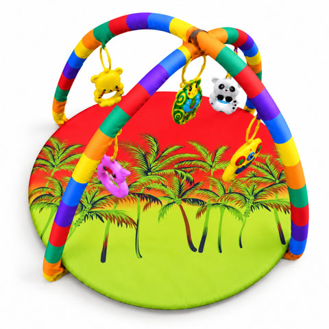 A colorful baby activity gym with rainbow-striped arches and hanging toys, set on a round mat printed with a tropical palm tree scene. The mat is bright red in the upper half and lime green in the lower half, photographed on a clean white background.