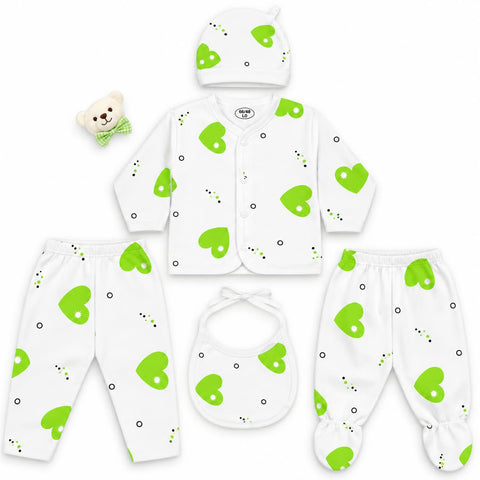 A baby clothing set laid out on a white background, including a long-sleeve button-front cardigan, matching footed pants, a bib, a hat, and a small teddy bear accessory. The items are white with bright green heart prints and small black dot accents.